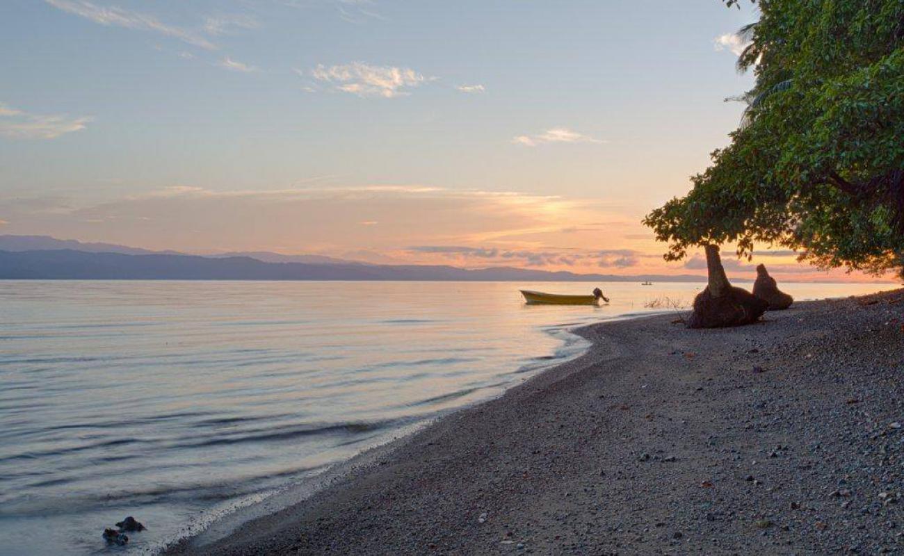 Фото Playa Juanito Mora с темная галька поверхностью