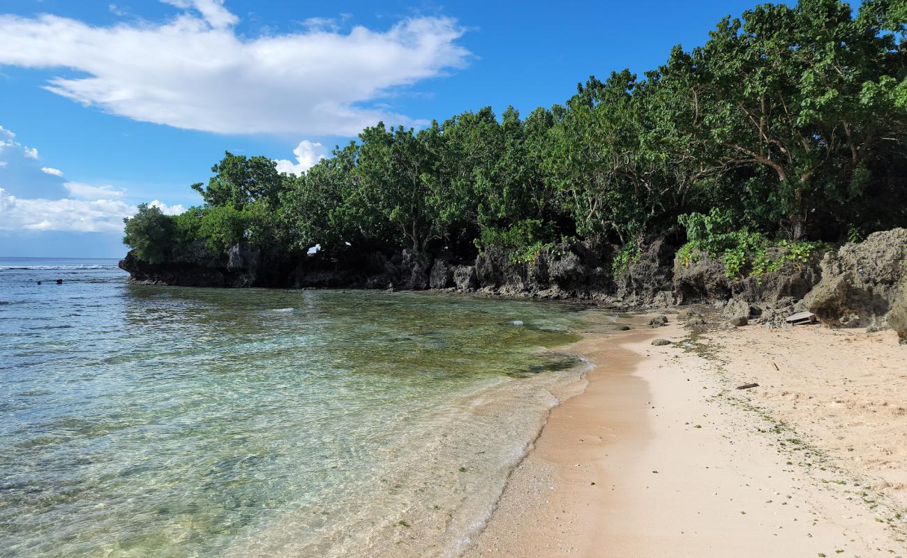 Фото Tanguisson Beach с песок с камнями поверхностью