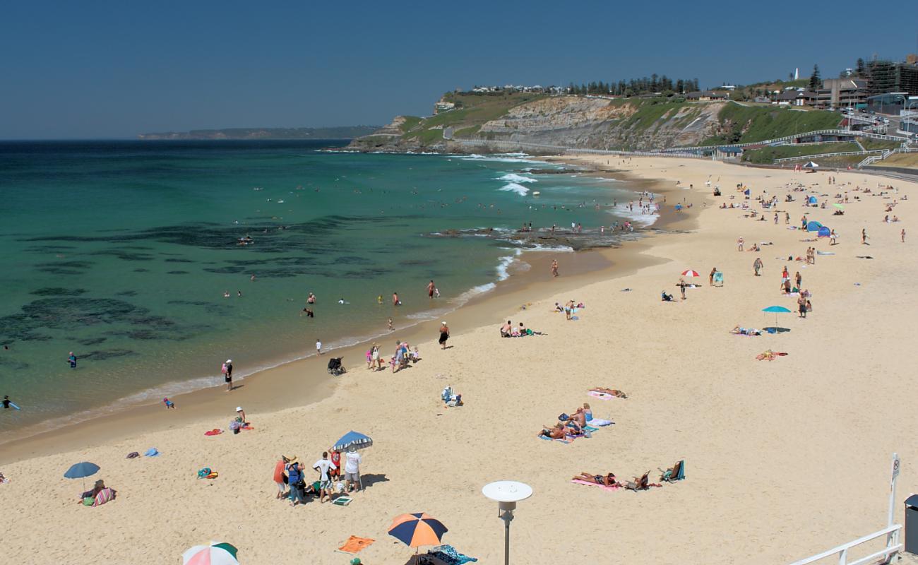 Фото Newcastle Beach с светлый песок поверхностью