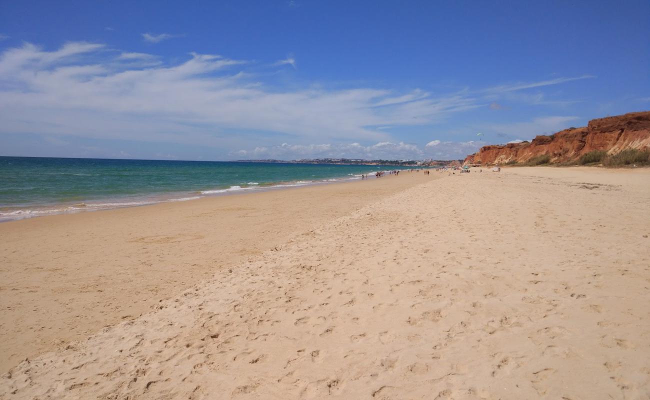 Фото Praia dos Tomates с темный чистый песок поверхностью