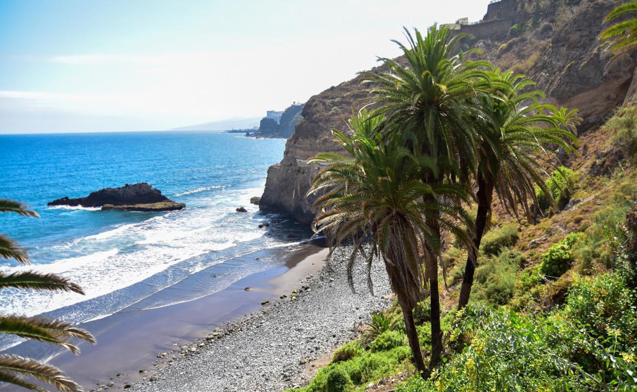 Фото Playa de la Fajana с серый песок поверхностью